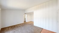 Located at 3700 Kingwood Drive in Houston, TX, this single-story unit offers a clean, functional layout with a straightforward design throughout. The living area is carpeted and benefits from abundant natural light provided by a full sliding glass door fitted with vertical blinds, which also offers direct access to an outdoor patio with exterior views. The entry point transitions from hard surface flooring at the front door into the carpeted main living space, creating a welcoming flow.

The galley-style kitchen is a standout feature, outfitted with rich dark espresso cabinetry, granite countertops, a stainless steel undermount sink with a modern pull-down faucet, and light hardwood-style flooring. Black appliances, including a refrigerator and range, complement the cabinetry. A window above the sink allows natural light to filter into the kitchen.

The bedroom areas are carpeted and feature neutral white walls, offering a clean and versatile backdrop. One bedroom includes a ceiling fan with light fixture and a window with exterior views, while the primary bedroom area opens into a walk-in closet. A vanity area with granite countertops and dark cabinetry connects to the bathroom corridor. The overall aesthetic is bright, neutral, and move-in ready throughout.