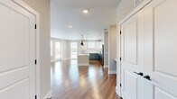 This single-floor, 2-bedroom, 2-bathroom residence offers a thoughtfully designed open-concept layout that seamlessly connects the entrance, living room, and kitchen. Rich hardwood-style flooring flows throughout, complemented by neutral warm-beige walls and recessed lighting that enhance the bright, airy atmosphere. The kitchen is a standout feature, boasting two-tone cabinetry — soft blue-green lower cabinets paired with white upper cabinets — accented by gold hardware and a white tile backsplash. Stainless steel appliances, including a refrigerator, range, and microwave, add a polished, modern touch, while a central island provides additional prep and dining space. The living area benefits from generous natural light through multiple windows and offers access to an outdoor balcony. Both bedrooms are comfortably sized, each with hardwood-style flooring, ceiling fans, and windows that invite natural light. The primary bedroom includes a dedicated closet with built-in wire shelving systems for ample storage. The bathrooms echo the home's design palette, featuring blue-green vanity cabinetry with gold fixtures, white countertops, and large framed mirrors. Two closets provide additional storage throughout the residence.