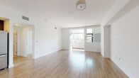 This single-floor residence offers a clean, modern aesthetic throughout, characterized by crisp white walls, light wood-tone flooring, and abundant natural light. The open-plan living area is spacious and airy, anchored by large sliding glass doors that lead to a private balcony with views of the surrounding urban skyline. The seamless connection between indoor and outdoor space enhances the sense of openness and keeps the interior filled with natural light throughout the day.

The kitchen is thoughtfully designed with rich dark espresso cabinetry, light quartz countertops, a subway tile backsplash, and a full suite of stainless steel appliances including a gas range, built-in microwave, dishwasher, and refrigerator. Recessed lighting highlights the workspace, making it both functional and visually striking.

The bedrooms are well-proportioned, each featuring the same warm wood-tone flooring and large windows that frame urban views while drawing in generous daylight. The bathroom is finished with neutral tile flooring, a dark vanity with a white countertop, and a glass-enclosed shower-tub combination, offering a clean and functional layout.

Throughout the unit, the design prioritizes a bright, minimalist aesthetic with consistent finishes that create a cohesive and inviting living environment.