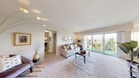 Located at 1934 Kennedy Dr in McLean, Virginia, this single-floor residence offers a well-organized and cohesive layout designed for comfortable everyday living. A light-filled hallway with light wood-style flooring and tasteful wall décor serves as the entry point, connecting the various areas of the home seamlessly.

The living room is a standout space, featuring plush carpeting, neutral walls, and a large sliding glass door that opens to a private balcony with outdoor seating and leafy views — allowing natural light to pour in throughout the day. Adjacent to the living area is a dedicated dining space with a carpeted floor, sheer-curtained windows, and room for a full dining table set.

The galley-style kitchen is efficiently laid out with warm wood cabinetry, laminate countertops, and white appliances including a gas range and refrigerator. Light wood-style flooring adds a clean, modern touch. A dedicated laundry area features a stacked washer and dryer unit alongside built-in shelving for organization.

The bedroom is a comfortable retreat with soft carpeting, ample space, and a warm, restful ambiance. The full bathroom offers white subway tile wainscoting, a vanity with a single sink, and practical overhead storage. Throughout the residence, a neutral color palette and consistent finishes create a cohesive and inviting atmosphere.