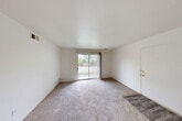 Located at 898 E Grand River Rd in Brighton, Michigan, this 2-bedroom, 1-bathroom residence offers a practical and well-organized single-floor layout. The bright living room features neutral carpet flooring and a sliding glass door that opens directly onto a private balcony, allowing natural light to fill the space while providing pleasant outdoor views of the surrounding greenery.

The galley-style kitchen is efficiently designed with light wood cabinetry, gray countertops, hardwood-style flooring, a gas range, a refrigerator, and a single-basin sink. It flows into a combined dining area that includes a ceiling fan and additional cabinet storage, creating a functional everyday living space.

Both bedrooms are carpeted and finished with neutral white walls. The primary bedroom includes a built-in closet with bi-fold doors and a window dressed with vertical blinds. The second bedroom also benefits from natural light through its own window. A hallway connects the main areas of the unit, and four closets distributed throughout provide ample storage. The bathroom features a tiled tub-and-shower surround in a clean, all-white finish. Throughout the unit, the consistent use of light tones and neutral finishes creates a cohesive, understated aesthetic.