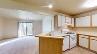 Located at 2274 E Cork St in Kalamazoo, Michigan, this single-floor unit offers a practical and comfortable layout with a neutral palette throughout. The kitchen is well-appointed with oak-trimmed white cabinetry, a gas range, and a peninsula with a built-in sink that opens directly to the living area. Tile flooring in the kitchen provides durability, while the transition into the living space reveals plush carpeting and vaulted ceilings that lend a sense of openness. A large sliding glass door in the living area frames views of surrounding trees and connects to an outdoor balcony, filling the space with natural light. The bedrooms are carpeted and feature windows with blinds, offering a quiet and bright retreat. One bedroom also benefits from sliding glass door access to the balcony. The bathroom is clean and functional, featuring tile flooring, a combination tub and shower, a toilet, and a vanity with wood cabinetry. Throughout the unit, the design is straightforward and neutral, making it easy to personalize while providing all essential amenities in a well-organized single-level floor plan.