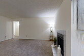 This single-floor residence offers a thoughtfully designed layout with two bedrooms, two bathrooms, and a comfortable variety of living spaces. The spacious living room serves as the heart of the home, featuring plush carpeting, a textured ceiling, and a striking tiled fireplace that anchors the room with warmth and character. Natural light filters in through window blinds, creating a bright and inviting atmosphere.

The galley-style kitchen is efficiently arranged with warm wood cabinetry, granite-toned countertops, and hardwood-style flooring. Black appliances, including a full-size refrigerator and range, complement the rich cabinetry tones, while a skylight adds brightness to the workspace.

The generously sized primary bedroom offers carpet flooring, a ceiling fan, built-in shelving, and direct access to an en-suite bathroom. The en-suite features a wood vanity with granite-style countertop, a large mirror, and a tub-shower combination. The second bedroom is equally well-sized with its own ceiling fan and closet access. The second bathroom features earthy tile surrounds and a tub-shower combination.

Additional highlights include a dedicated laundry room, five closets distributed throughout for ample storage, a separate dining room, and a connecting hallway that ties the layout together seamlessly.
