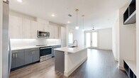 This well-appointed 2-bedroom, 3-bathroom single-floor residence offers a thoughtfully designed open-concept layout with modern finishes throughout. The combined kitchen and living area serves as the heart of the home, featuring a central island with a built-in sink, sleek white quartz countertops, and dual-tone cabinetry with light upper cabinets and slate-blue lower cabinets accented by gold hardware. Stainless steel appliances, a white subway tile backsplash, and globe pendant lights with brass fixtures add a contemporary touch. The living area extends seamlessly from the kitchen, bathed in natural light from French doors and is equipped with a ceiling fan. Wide-plank wood-look flooring runs throughout the entire space, providing a cohesive aesthetic. The two bedrooms are bright and airy, each featuring large windows with views of the surrounding area, ceiling fixtures, and neutral wall tones. The primary bedroom includes a dedicated closet with built-in shelving and hanging rods for organized storage. The bathrooms are finished to a high standard, with at least one featuring a walk-in glass-enclosed shower with large-format tile, a built-in niche, and a bench seat. Two hallways and two closets complete the functional layout of this well-designed residence.