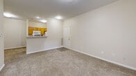 Located at 711 Greenridge Dr E in Brownsburg, Indiana, this single-floor unit offers a practical and well-organized layout designed for efficient living. The interior features neutral beige walls and consistent wall-to-wall carpeting throughout, creating a warm and cohesive aesthetic across all spaces.

The living area is open and inviting, with a pass-through kitchen counter featuring warm wood-toned cabinetry and built-in appliances, including a microwave. A front entry door provides direct access to the living space, while a vent register and clean white trim work complete the room's tidy finish. The layout flows naturally from the main living area through a hallway that connects to the rest of the unit.

The bedroom is a comfortable, well-proportioned space bathed in natural light from two windows that overlook greenery outdoors. A panel closet door provides ample storage, and the soft carpeting continues throughout. An additional room off the hallway features a glass-paned exterior door with a view of outdoor greenery, offering a bright and airy atmosphere.

Clean white baseboards and neutral tones throughout lend the space a move-in-ready feel. The straightforward, efficient floor plan makes excellent use of every square foot, offering a functional and comfortable living environment in a residential Brownsburg neighborhood.