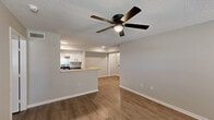 Located at 2121 N Lobdell Blvd in Baton Rouge, Louisiana, this single-story, three-bedroom, two-bathroom home offers a functional and well-appointed layout throughout. Wood-look flooring flows consistently across the living areas and bedrooms, complemented by neutral gray walls and white trim that create a clean, cohesive aesthetic. The open living room features a ceiling fan and connects seamlessly to the kitchen via a breakfast bar peninsula, making the space feel connected and practical. The kitchen is equipped with white cabinetry, dark granite-style countertops, a stainless steel refrigerator, and an electric range, providing ample storage and prep space. Each of the three bedrooms includes a ceiling fan with light and windows with blinds that allow for natural light, with the primary bedroom offering a walk-in closet fitted with wire shelving on both sides. Both bathrooms feature white vanities with undermount sinks, tub-shower combinations with tiled surrounds, and wood-look flooring. A hallway connects the bedrooms and bathrooms, keeping the layout organized and efficient. Textured ceilings are present throughout the home, adding a classic touch to the overall design.