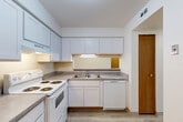 Located at 5800 Benson Dr in Haslett, MI, this single-floor one-bedroom unit offers a practical and comfortable layout across a thoughtfully organized floor plan. The combined living and dining area is bright and open, finished with light-toned luxury vinyl plank flooring and anchored by a ceiling fan with light fixture. A pass-through window connects this space directly to the kitchen, enhancing the open feel. The kitchen is well-appointed with white shaker-style cabinetry, ample upper and lower storage, a double-basin stainless steel sink, a full suite of white appliances including an electric range and dishwasher, and a dedicated pantry for additional storage. A light-filled hallway with flush-mount lighting connects the main living area to the bedroom and bathroom. The bedroom features plush wall-to-wall carpeting, a large window with vertical blinds for natural light and privacy, and a full-width sliding closet. Two additional closets provide generous storage throughout the unit. A sliding glass door opens to a private balcony overlooking a lush green landscape, offering a serene outdoor retreat. The overall aesthetic is clean and neutral, with white walls and wood-toned doors and trim throughout.