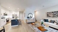 Located in Highland, CA, this two-story home offers 2 bedrooms and 3 bathrooms across two well-proportioned floors. The main level features an open-concept layout seamlessly connecting the living room, dining area, and kitchen. The living room is bright and welcoming, with large windows dressed in Roman shades that invite natural light onto wide-plank light wood flooring. The kitchen is a standout, showcasing crisp white shaker cabinetry with matte black hardware, a bold navy blue island with bar seating, white quartz countertops, a subway tile backsplash, and stainless steel appliances. The adjacent dining area provides a defined space complete with light wood flooring and clean wall lines. A half bathroom is also conveniently located on the main floor. Upstairs, the two bedrooms feature plush carpeting and windows with ample natural light. The primary bedroom includes a walk-in closet with built-in shelving and hanging rods. The bathrooms are finished with neutral tones, clean white vanities, and wood-look tile flooring. Throughout the home, a consistent modern aesthetic is maintained with a neutral color palette, recessed lighting, and smooth transitions between spaces.