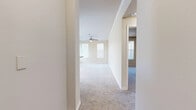 This single-story unit offers a thoughtfully organized layout across a compact yet efficient floor plan. The living area is finished with plush carpeting, crown molding, and a ceiling fan, while multiple windows fitted with horizontal blinds allow natural light to brighten the neutral-toned walls. A door provides direct exterior access, adding convenience.

The kitchen is designed with practicality in mind, featuring a breakfast bar with granite-style countertops that opens toward the living space. Dark-stained cabinetry provides ample storage, and black appliances—including a refrigerator, range, and microwave—are included. Wood-look hard flooring runs throughout the kitchen, offering a clean contrast to the carpeted areas. A set of double doors in the kitchen leads to additional storage or a closet.

The bedroom is a well-proportioned, carpeted room with a ceiling fan, a large window for natural light, and sufficient wall space for furniture arrangement. A dedicated closet serves the bedroom for organized storage.

The bathroom is finished with rich, dark wood cabinetry, granite-style countertops, a tiled tub-shower combination, and wood-look flooring, creating a cohesive and polished aesthetic. A hallway connects the rooms, contributing to a functional and efficient flow throughout the unit.