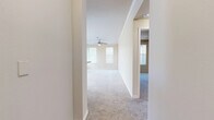 This single-story unit offers a thoughtfully organized layout across a compact yet efficient floor plan. The living area is finished with plush carpeting, crown molding, and a ceiling fan, while multiple windows fitted with horizontal blinds allow natural light to brighten the neutral-toned walls. A door provides direct exterior access, adding convenience.

The kitchen is designed with practicality in mind, featuring a breakfast bar with granite-style countertops that opens toward the living space. Dark-stained cabinetry provides ample storage, and black appliances—including a refrigerator, range, and microwave—are included. Wood-look hard flooring runs throughout the kitchen, offering a clean contrast to the carpeted areas. A set of double doors in the kitchen leads to additional storage or a closet.

The bedroom is a well-proportioned, carpeted room with a ceiling fan, a large window for natural light, and sufficient wall space for furniture arrangement. A dedicated closet serves the bedroom for organized storage.

The bathroom is finished with rich, dark wood cabinetry, granite-style countertops, a tiled tub-shower combination, and wood-look flooring, creating a cohesive and polished aesthetic. A hallway connects the rooms, contributing to a functional and efficient flow throughout the unit.