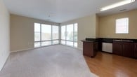 This 1-bedroom, 1-bathroom unit is thoughtfully designed across a single floor, offering a functional and comfortable layout. The open living area is a standout feature, anchored by expansive floor-to-ceiling corner windows that flood the space with natural light and provide sweeping outdoor views of the surrounding greenery. Plush wall-to-wall carpeting in the living and bedroom areas adds warmth underfoot, while light wood-style flooring defines the kitchen zone.

The kitchen is well-equipped with rich dark wood cabinetry, sleek black granite countertops, and a full suite of stainless steel appliances including a range with overhead microwave and a refrigerator. A breakfast bar peninsula with matching cabinetry bridges the kitchen and living area, enhancing the open-concept feel.

The bedroom is a bright and peaceful retreat, featuring a large window with exterior views, soft carpeting, and a ceiling fan for year-round comfort. The full bathroom is clean and functional, finished with tile flooring, a tub/shower combo, dark wood wall cabinetry for storage, and classic white fixtures with brushed nickel hardware. Neutral wall tones throughout create a cohesive, move-in-ready aesthetic.