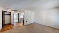 This efficient single-floor unit offers a thoughtfully arranged layout that maximizes functionality across its compact footprint. The combined living and kitchen area forms the heart of the home, where warm hardwood-style flooring transitions to soft carpeting in the living space. A textured ceiling and neutral white walls provide a clean, bright backdrop throughout.

The galley-style kitchen is well-equipped, featuring gray cabinetry with modern hardware, light granite-look countertops, a stainless steel sink, and stainless steel appliances including a refrigerator and range. Ample upper and lower cabinet storage makes the most of the space.

The living area is an open, carpeted space that benefits from natural light filtering in through a window overlooking a balcony or outdoor area. A dedicated closet provides convenient additional storage.

The bedroom is a comfortable, carpeted retreat with crisp white walls, a textured ceiling, a window dressed with horizontal blinds for natural light and privacy, and a louvered closet door for built-in storage.

The full bathroom features a combination tub and shower, a toilet, and a vanity, all set on warm hardwood-style flooring with clean white walls and chrome fixtures, completing this practical and well-maintained unit.