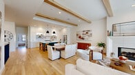 Located at 730 S Norfolk Ave in Tulsa, Oklahoma, this well-appointed two-story home offers four bedrooms and four bathrooms across a thoughtfully designed layout. The main floor sets an inviting tone with an open-concept living, dining, and kitchen area unified by warm hardwood flooring and striking exposed wood ceiling beams. The kitchen is a standout feature, boasting white shaker cabinetry with brass hardware, a decorative tile backsplash, stainless steel appliances including a professional-grade range, open shelving, and a bold teal island with bar seating. The adjacent living room is anchored by a shiplap fireplace and large black-framed windows that fill the space with natural light. A well-equipped laundry room with dark cabinetry, a utility sink, and tile flooring adds convenience to the main level, along with an attached garage with a concrete floor and electrical panel. Upstairs, the generously sized primary bedroom features plush carpet, a ceiling fan, and multiple windows offering outdoor views. Walk-in closets with built-in shelving and rods provide ample storage. The bathrooms exhibit tasteful finishes, including patterned tile flooring. Throughout, the home maintains a clean, modern aesthetic with a warm, neutral palette.