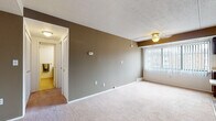 Located at Columbia Square in North Olmsted, Ohio, this single-floor residence offers a practical and functional layout designed for comfortable everyday living. The open-concept living and dining area is generously sized, featuring neutral-toned carpet, a textured ceiling, a ceiling fan, and a taupe accent wall that adds visual depth. Vertical blinds on the window allow for adjustable natural light throughout the space.

The galley-style kitchen is efficiently arranged with rich dark wood cabinetry lining both sides, light countertops, hardwood-style flooring, and white appliances including a range and refrigerator. A built-in dishwasher and single-basin sink complete the kitchen's functional offerings.

The unit includes multiple bedrooms, each carpeted and featuring louvered bi-fold closet doors. Windows in the bedrooms provide natural light and views of the surrounding community. The rooms offer clean, neutral walls suited for a variety of uses.

The bathroom is appointed with a classic mosaic tile floor in a cream and burgundy pattern, a wood-toned vanity with countertop sink, a full soaking tub with shower, and a separate glass-enclosed shower stall. The overall layout is straightforward and well-maintained, offering a move-in ready living environment.