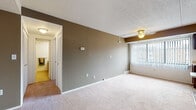 Located at Columbia Square in North Olmsted, Ohio, this single-floor residence offers a practical and functional layout designed for comfortable everyday living. The open-concept living and dining area is generously sized, featuring neutral-toned carpet, a textured ceiling, a ceiling fan, and a taupe accent wall that adds visual depth. Vertical blinds on the window allow for adjustable natural light throughout the space.

The galley-style kitchen is efficiently arranged with rich dark wood cabinetry lining both sides, light countertops, hardwood-style flooring, and white appliances including a range and refrigerator. A built-in dishwasher and single-basin sink complete the kitchen's functional offerings.

The unit includes multiple bedrooms, each carpeted and featuring louvered bi-fold closet doors. Windows in the bedrooms provide natural light and views of the surrounding community. The rooms offer clean, neutral walls suited for a variety of uses.

The bathroom is appointed with a classic mosaic tile floor in a cream and burgundy pattern, a wood-toned vanity with countertop sink, a full soaking tub with shower, and a separate glass-enclosed shower stall. The overall layout is straightforward and well-maintained, offering a move-in ready living environment.