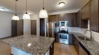 Located at 9635 Westland Cove Way in Knoxville, Tennessee, this single-floor residence offers a well-designed, open layout with modern finishes throughout. The kitchen is a standout feature, showcasing rich dark cabinetry, granite countertops, a tile backsplash, and a full suite of stainless steel appliances including a refrigerator, range, and built-in microwave. A central island with pendant lighting above provides additional prep space and separates the kitchen from the open living area, which features light-toned hardwood-style flooring. The bedroom is carpeted and includes a ceiling fan with light fixture, offering a comfortable and well-ventilated retreat. Two walk-in closets with wire shelving systems provide generous storage capacity. The bathrooms are finished with granite-topped dark wood vanities, and one bathroom features a full soaking tub with tile surround and a window for natural light, while another offers a sleek vanity with modern lighting. A dedicated in-unit laundry closet houses a full-size washer and dryer. Dark-trimmed interior doors and neutral wall tones contribute to a cohesive, contemporary aesthetic throughout the space.