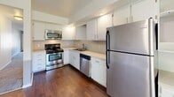 Located at 900 Long Blvd in Lansing, Michigan, this single-floor unit offers a thoughtfully organized layout encompassing a living room, bedroom, bathroom, combined dining room and kitchen, and a dedicated closet. The living room features neutral taupe walls, soft carpeting, and a front-facing window that brings in natural light alongside a standard entry door. A hallway connects the main living areas, leading toward the bedroom and kitchen. The bedroom is a generously sized room with plush carpeting, bright white walls, and a window overlooking lush greenery, creating a calm and restful atmosphere. A built-in vanity area with shelving and a walk-in closet add practical storage and convenience. The combined kitchen and dining area is a functional highlight, featuring stainless steel appliances including a refrigerator, range, microwave, and dishwasher, complemented by white cabinetry, light countertops, and rich dark hardwood flooring. A sliding glass door offers direct outdoor access and fills the space with natural light. The bathroom is finished with tile flooring, a white vanity with ample drawer storage, and a full tub-shower combination with grab bars, providing both comfort and accessibility.