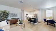 Located at 28214 Greenspot Rd in Highland, CA, this thoughtfully designed 1-bedroom, 1-bathroom residence offers a clean, contemporary aesthetic with efficient, well-organized living spaces across a single floor. The open-concept main area seamlessly connects the living room, dining area, and kitchen, creating a cohesive and functional layout. The kitchen is a standout feature, showcasing crisp white shaker cabinetry extending to the ceiling, a classic subway tile backsplash, quartz countertops, stainless steel appliances, and a dark-finished island with seating for two — ideal for casual dining or entertaining. Light wood-look flooring flows throughout the main living areas, lending warmth and continuity. The living room offers a comfortable, open feel with recessed lighting overhead, while the adjacent dining nook benefits from natural light streaming through a window dressed with patterned curtains. The bedroom is a calm retreat featuring plush carpeting, a window with natural light, and a dedicated closet. The bathroom is finished in crisp white tones with a tub-shower combination and a white vanity. Additional conveniences include an in-unit laundry area, ample storage, and a staircase providing access to additional levels of the building.
