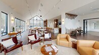 Located at 6461 US Hwy 9 in Howell, NJ, this thoughtfully designed single-floor amenity space offers a sophisticated blend of comfort and functionality across a generous footprint. The welcoming entrance lobby features warm wood-slat accent columns, rich hardwood flooring, and expansive floor-to-ceiling windows that flood the space with natural light and offer views of the surrounding community.

The living room is the centerpiece of the space, boasting soaring vaulted ceilings with a dramatic gabled window wall, track lighting, and a curated mix of mid-century modern furnishings including leather lounge chairs, a neutral sectional sofa, and a tile-clad fireplace. This area flows seamlessly into a dining lounge equipped with a marble-accented kitchen bar, pendant lighting, built-in wooden shelving with books, and a wall-mounted TV — ideal for gathering and socializing.

The exercise room is fully outfitted with treadmills, ellipticals, stationary bikes, free weights, medicine balls, and resistance machines, all set on durable rubber flooring with mirrored walls and a mounted display screen. An adjacent open studio room with carpet flooring and a large wall mirror provides a versatile space for yoga, stretching, or group fitness activities. Together, these areas create a well-rounded, community-oriented environment designed for both relaxation and an active lifestyle.