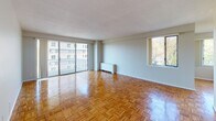 This single-floor residence offers a thoughtfully laid-out living space characterized by gleaming parquet hardwood flooring that flows consistently throughout every room, lending warmth and a timeless aesthetic to the interior. The spacious main living area is bathed in natural light, courtesy of large sliding glass doors that open onto a private balcony overlooking the surrounding neighborhood. An additional window further brightens the space and frames views of the outdoors, creating an airy, open atmosphere. The living area is generously proportioned, offering ample room for a variety of furniture arrangements.

The bedroom features the same polished parquet flooring and includes a built-in closet with bifold doors, providing practical storage. A window in the bedroom allows for natural light and neighborhood views.

The kitchen is equipped with white cabinetry, a coil electric range, an overhead exhaust hood, dark granite-style countertops, a refrigerator, and tiled backsplash — a functional and efficient space for everyday cooking.

The bathroom is finished in classic white, featuring small mosaic floor tiles, a vanity with white cabinetry, a toilet, and grab bars for added accessibility. Neutral-toned walls throughout the residence create a clean, versatile backdrop ready for personalization.
