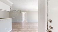 This single-floor unit offers a smart and efficient layout designed to maximize every square foot. The open-concept living, dining, and kitchen area forms the heart of the home, featuring light wood-look flooring, neutral gray walls, and a textured ceiling throughout. A sliding glass door floods the living area with natural light and provides outdoor access. The kitchen is defined by a peninsula counter with a speckled quartz-style surface, white cabinetry, a sink, and black appliances including a refrigerator and range with overhead ventilation. Adjacent to the main living space, the dining area flows seamlessly into the rest of the unit. A hallway connects to the private bedroom, which is generously sized and features plush carpeting, a ceiling fan with light fixture, and a window that invites natural light. The full bathroom is clean and functional, offering a shower/tub combo, a vanity with a speckled countertop, white cabinetry, and wood-look flooring. Storage is a standout feature of this unit, with three closets including a spacious walk-in closet outfitted with built-in shelving and hanging rods. The overall aesthetic is neutral, bright, and move-in ready.
