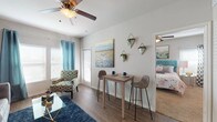 Located at 1747 FM 1101 in New Braunfels, Texas, this single-floor residence offers a thoughtfully designed layout that seamlessly connects its main living areas. The open-concept living and dining space features warm wood-look flooring, neutral walls, and ceiling fans throughout, creating a comfortable and functional atmosphere. Natural light filters in through white plantation-shuttered windows accented by teal curtains, lending the space a bright and inviting feel.

The kitchen is well-equipped with dark espresso cabinetry, granite-style countertops, a kitchen island, and a full suite of black appliances including a refrigerator, range, microwave, and dishwasher. The wood-look flooring continues into the kitchen, maintaining a cohesive aesthetic throughout the main living areas.

The bedroom is a serene retreat, featuring plush carpeting, ceiling fan, multiple windows with plantation shutters, and access to a walk-in closet. The room offers ample space for a full furniture arrangement and connects conveniently to the rest of the unit.

The bathroom includes a full tub-shower combination with white tile surround, complemented by clean, simple finishes. Throughout the residence, the consistent design choices — from flooring to fixtures — create a cohesive, comfortable living environment well-suited for everyday life in New Braunfels.