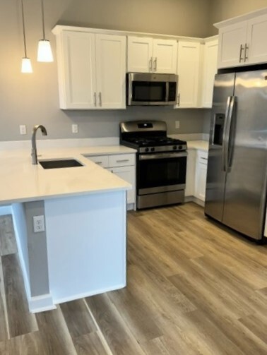 Tasteful galley kitchen with quartz counters, stainless steel appliances & wood cabinetry - 271 Millburn Ave