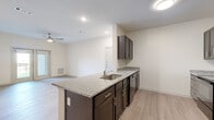 This 1-bedroom, 1-bathroom residence offers a thoughtfully laid-out single-floor plan with a clean, modern aesthetic throughout. Light-toned luxury vinyl plank flooring runs continuously through the main living areas, lending a cohesive and contemporary feel to the space.

The kitchen serves as a central hub, anchored by a granite-topped island with an undermount sink and dark espresso cabinetry. Full-size black stainless steel appliances—including a refrigerator, microwave, and dishwasher—complete the kitchen's functional and stylish design. The kitchen flows seamlessly into the open living room, which is fitted with a ceiling fan and French doors that open to a private balcony, bringing in natural light and outdoor views.

The bedroom is a comfortable, well-proportioned retreat featuring its own ceiling fan, a window with exterior views, and direct access to both a closet and the bathroom. The bathroom features large-format white tile flooring, dark vanity cabinetry with granite countertops, a full soaking tub with shower, and clean white walls that create a bright, functional space.

Throughout the residence, neutral wall tones, recessed lighting, and consistent finishes contribute to a bright, move-in-ready environment that is both practical and inviting.