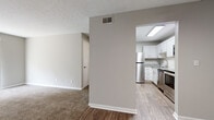 Located at 2810 De Mel Ave. in Louisville, Kentucky, this one-bedroom, one-bathroom unit offers a compact and efficiently designed single-floor layout. Neutral gray walls and white trim are consistent throughout, creating a clean, cohesive aesthetic. The living room features soft wall-to-wall carpeting and a large sliding glass door dressed with vertical blinds, allowing abundant natural light to fill the space. It connects openly to the rest of the unit, with a clear sightline into the kitchen. The kitchen is a standout feature, equipped with white shaker-style cabinetry, granite-look countertops, a white subway tile backsplash, and stainless steel appliances including a refrigerator, range, and built-in microwave. Wood-look vinyl plank flooring runs throughout the kitchen, adding warmth and durability. The bedroom is a comfortable size, finished with plush carpeting and a window fitted with horizontal blinds that provide both light and privacy. A textured ceiling is present throughout the unit. The bathroom includes a full tub-and-shower combination, wood-look flooring, and granite-look countertop details that echo the kitchen's finishes. Overall, the unit presents a well-maintained, move-in-ready interior with consistent modern updates throughout.