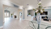 Located at 540 Hobbs Road in League City, Texas, this spacious single-floor facility offers a thoughtfully designed layout encompassing a wide variety of functional amenities. The entrance welcomes visitors with light-washed walls, light wood-look flooring, and clean crown molding that carry throughout the entire space, establishing a cohesive and polished aesthetic.

Multiple living areas provide versatile gathering spaces, while a bright dining room features large windows that flood the room with natural light and views of the surrounding neighborhood. A wall-mounted television adds a media-friendly touch to the dining area. The dedicated kitchen is outfitted with gray shaker-style cabinetry, a dishwasher, microwave, and ample counter space, supporting both everyday use and group functions.

A stylish game room serves as a social hub, complete with poker tables, a shuffleboard table, and framed artwork, all bathed in recessed lighting. Adjacent to it, a well-appointed bar area features a white countertop peninsula with bar seating, built-in shelving, and pendant ring lighting, perfect for hosting.

The fitness center is comprehensively equipped with cardio machines, weight equipment, resistance machines, free weights, exercise balls, and wall-mounted mirrors and a TV — offering a full workout experience. Hallways connect each area seamlessly, maintaining an open and navigable flow throughout this impressive, amenity-rich facility.