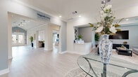 Located at 540 Hobbs Road in League City, Texas, this spacious single-floor facility offers a thoughtfully designed layout encompassing a wide variety of functional amenities. The entrance welcomes visitors with light-washed walls, light wood-look flooring, and clean crown molding that carry throughout the entire space, establishing a cohesive and polished aesthetic.

Multiple living areas provide versatile gathering spaces, while a bright dining room features large windows that flood the room with natural light and views of the surrounding neighborhood. A wall-mounted television adds a media-friendly touch to the dining area. The dedicated kitchen is outfitted with gray shaker-style cabinetry, a dishwasher, microwave, and ample counter space, supporting both everyday use and group functions.

A stylish game room serves as a social hub, complete with poker tables, a shuffleboard table, and framed artwork, all bathed in recessed lighting. Adjacent to it, a well-appointed bar area features a white countertop peninsula with bar seating, built-in shelving, and pendant ring lighting, perfect for hosting.

The fitness center is comprehensively equipped with cardio machines, weight equipment, resistance machines, free weights, exercise balls, and wall-mounted mirrors and a TV — offering a full workout experience. Hallways connect each area seamlessly, maintaining an open and navigable flow throughout this impressive, amenity-rich facility.