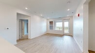 Located at 8870 Galaxy Way in Columbus, OH, this thoughtfully designed 2-bedroom, 2-bathroom residence offers a bright and modern single-floor layout. The open-concept kitchen and living area serves as the heart of the home, featuring light hardwood-style flooring, recessed lighting, and a seamless flow between spaces. The kitchen is well-appointed with gray shaker cabinetry, stainless steel appliances including a refrigerator, range, and microwave, a white quartz countertop island with an undermount sink, and elegant pendant lighting overhead. The living room is bathed in natural light from large windows and a glass door that opens onto a generously sized private patio. The patio features a warm wood-paneled accent wall, light composite decking, and open views of the surrounding landscape. Both bedrooms are carpeted for comfort, with the primary bedroom offering its own walk-in closet complete with dual wire shelving systems. The bathrooms are finished with gray shaker vanities, white quartz countertops, brushed nickel hardware, and full tub-shower combinations. Additional conveniences include a dedicated laundry area, utility room, entrance foyer, and three closets throughout for ample storage.
