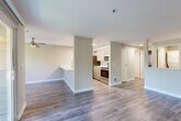 Located at 8935 160th Ave NE in Redmond, WA, this one-bedroom, one-bathroom residence offers a well-designed layout that maximizes every square foot. The open-concept living and kitchen area is anchored by durable wood-style flooring and filled with natural light from large windows and a sliding glass door that opens onto a private balcony overlooking lush tree canopy. A ceiling fan and a tile-surround fireplace add both comfort and character to the living room. The galley-style kitchen is appointed with light wood cabinetry, white quartz countertops, a stainless steel undermount sink, and a full suite of stainless steel appliances including a refrigerator, electric range, microwave, and dishwasher. A hallway connects the main living space to the bedroom, bathroom, closet, and laundry room. The bedroom features plush carpeting and direct access to a spacious walk-in closet outfitted with wire shelving. The bathroom includes wood-tone vanity cabinetry, a white quartz countertop, and a full tub/shower combination. A dedicated laundry room houses a stacked washer and dryer unit, adding everyday convenience to this thoughtfully appointed Redmond residence.