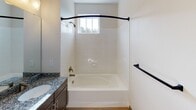 This single-floor residence at 9635 Westland Cove Way in Knoxville, Tennessee offers a well-designed layout with modern finishes throughout. The kitchen serves as a central highlight, featuring rich dark cabinetry, granite countertops, a subway tile backsplash, and a full suite of stainless steel appliances including a refrigerator, range, microwave, and dishwasher. A substantial kitchen island with matching granite provides additional prep space and is illuminated by three stylish pendant lights. Light wood-style flooring runs through the kitchen and main living areas, creating a warm and cohesive aesthetic. The bedrooms are carpeted for comfort, with one featuring a walk-in closet with wire shelving and another offering a double-door closet. The primary bathroom includes a granite-topped vanity, wood-style flooring, and a glass-enclosed walk-in shower. A secondary bathroom provides a tiled tub-shower combination with a window for natural light. Throughout the space, neutral wall tones and consistent dark-trimmed doors and hardware create a clean, unified style. The open-concept flow between the kitchen and living areas makes the space feel welcoming and functional, suited for everyday living.
