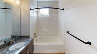 This single-floor residence at 9635 Westland Cove Way in Knoxville, Tennessee offers a well-designed layout with modern finishes throughout. The kitchen serves as a central highlight, featuring rich dark cabinetry, granite countertops, a subway tile backsplash, and a full suite of stainless steel appliances including a refrigerator, range, microwave, and dishwasher. A substantial kitchen island with matching granite provides additional prep space and is illuminated by three stylish pendant lights. Light wood-style flooring runs through the kitchen and main living areas, creating a warm and cohesive aesthetic. The bedrooms are carpeted for comfort, with one featuring a walk-in closet with wire shelving and another offering a double-door closet. The primary bathroom includes a granite-topped vanity, wood-style flooring, and a glass-enclosed walk-in shower. A secondary bathroom provides a tiled tub-shower combination with a window for natural light. Throughout the space, neutral wall tones and consistent dark-trimmed doors and hardware create a clean, unified style. The open-concept flow between the kitchen and living areas makes the space feel welcoming and functional, suited for everyday living.