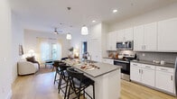Located at 3901 E Parmer Ln in Manor, TX, this 2-bedroom, 3-bathroom residence offers a thoughtfully designed single-story layout with contemporary finishes throughout. Light wood-style flooring flows seamlessly across the living spaces, lending warmth and visual continuity.

The kitchen is a standout feature, showcasing white shaker cabinetry, grey quartz countertops, a textured tile backsplash, stainless steel appliances, and a spacious island with seating for multiple guests — ideal for both cooking and casual dining. Pendant lighting above the island adds a polished touch.

The open living room benefits from natural light streaming through a glass exterior door dressed in sheer curtains, creating an airy and welcoming atmosphere. A ceiling fan adds comfort to the space.

Both bedrooms are comfortably sized, with the primary bedroom offering generous proportions, natural light from well-positioned windows, and light-toned flooring. Each bedroom features ceiling fans and drapery for privacy and light control.

The three bathrooms are finished with white cabinetry, grey countertops, large-format tile flooring, and full mirrors. One bathroom includes a soaking tub with tiled surround. A dedicated closet provides additional storage. The overall design is clean, modern, and functional.