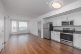 Located at 417 Centinela Ave in Inglewood, California, this well-appointed 2-bedroom, 2-bathroom residence offers a clean, modern aesthetic throughout its single-floor layout. Warm hardwood flooring flows seamlessly through every room, creating a cohesive and inviting ambiance.

The open-concept kitchen and living area forms the heart of the home. The kitchen is outfitted with stainless steel appliances — including a refrigerator, range, microwave, and dishwasher — complemented by white cabinetry, dark countertops, and a sink with ample workspace. This layout allows for easy interaction between the kitchen and living areas.

The spacious primary bedroom features large windows with blinds, allowing abundant natural light and views of the surrounding neighborhood, including palm tree-lined streetscapes. The second bedroom is equally well-lit, with its own window and generous floor space. Both rooms offer a calm, neutral palette with white walls and polished hardwood floors.

The two bathrooms are finished in a clean, modern style, each featuring a tub-shower combination with white subway tile surround, a vessel sink atop white cabinetry with dark countertops, and hardwood flooring. Additional highlights include three closets, a dedicated laundry area, and a welcoming entrance foyer, rounding out this thoughtfully designed residence.