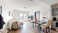 Located at 1911 Belcourt Ave in Nashville, Tennessee, this one-bedroom, one-bathroom unit offers a well-designed layout that maximizes its compact footprint. The open-concept living and dining area is anchored by light wood-tone flooring, crisp white walls, and a track-lit ceiling, creating a bright and airy atmosphere throughout. A set of glass sliding doors leads to a private balcony, flooding the space with natural light and offering elevated views of the surrounding Nashville neighborhood.

The kitchen flows seamlessly from the dining area and features gray shaker-style cabinetry, white subway tile backsplash, stainless steel appliances, and ample counter space — a functional and stylish setup for everyday cooking. A dedicated dining area sits adjacent, providing a natural transition between the kitchen and living room.

The bedroom is carpeted for comfort, benefits from a large window with sheer curtains that allow soft natural light, and is accessed via a sliding barn-style door. A dedicated closet with built-in shelving provides organized storage.

The bathroom showcases a gray vanity with dark countertops and a large mirror, and the hallway leading to it conveniently houses a stacked in-unit washer and dryer. Overall, the space presents a clean, modern aesthetic with practical amenities throughout.