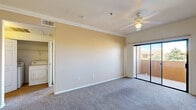 This single-floor, one-bedroom, one-bathroom unit offers a practical and comfortable layout across a compact yet efficiently designed footprint. The combined kitchen and living room forms the heart of the home, with the living area featuring warm neutral-toned carpet, crown molding, a ceiling fan with light fixture, and a sliding glass door that opens to a private balcony with outdoor views. The kitchen is well-equipped with ample warm-toned wood cabinetry, generous counter space, and a full suite of black appliances including a gas range, built-in microwave, dishwasher, and refrigerator, all set atop easy-care tile flooring. The bedroom is a comfortable, carpeted retreat filled with natural light from a large window, complemented by a ceiling fan and access to a spacious walk-in closet outfitted with wire shelving and hanging rods. The bathroom features tile flooring, a tiled tub-shower combination, a vanity with a dark countertop, and warm wood cabinetry. A hallway connects the main living spaces, and in-unit laundry hookups add everyday convenience. Throughout, warm beige tones and consistent finishes create a cohesive and inviting ambiance.