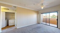 This single-floor, one-bedroom, one-bathroom unit offers a practical and comfortable layout across a compact yet efficiently designed footprint. The combined kitchen and living room forms the heart of the home, with the living area featuring warm neutral-toned carpet, crown molding, a ceiling fan with light fixture, and a sliding glass door that opens to a private balcony with outdoor views. The kitchen is well-equipped with ample warm-toned wood cabinetry, generous counter space, and a full suite of black appliances including a gas range, built-in microwave, dishwasher, and refrigerator, all set atop easy-care tile flooring. The bedroom is a comfortable, carpeted retreat filled with natural light from a large window, complemented by a ceiling fan and access to a spacious walk-in closet outfitted with wire shelving and hanging rods. The bathroom features tile flooring, a tiled tub-shower combination, a vanity with a dark countertop, and warm wood cabinetry. A hallway connects the main living spaces, and in-unit laundry hookups add everyday convenience. Throughout, warm beige tones and consistent finishes create a cohesive and inviting ambiance.