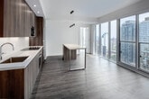 Located in the heart of Toronto at 8 Gloucester Street, this modern 2-bedroom, 2-bathroom unit offers a well-designed layout with contemporary finishes throughout. The open-concept kitchen is a standout feature, showcasing floor-to-ceiling wood-grain cabinetry, integrated stainless steel appliances including a built-in microwave, wall oven, and refrigerator, paired with clean white countertops and a stylish breakfast bar with pendant lighting — ideal for both cooking and casual dining. Warm hardwood-style flooring flows seamlessly throughout the unit, complementing the bright, white walls and recessed lighting. The bedrooms are well-proportioned, with the primary bedroom offering generous closet space with built-in shelving and sliding doors. Floor-to-ceiling windows flood the living areas with natural light and frame striking high-rise views of the Toronto skyline. Both bathrooms are finished with grey stone-effect tile surrounds, wood-toned floating vanities, white countertops, and mirrored medicine cabinets — one featuring a glass-enclosed shower, the other a full soaking tub. The hallways connect the spaces efficiently, contributing to a clean and functional flow throughout this smartly designed urban residence.