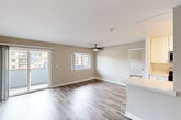 This single-floor, 2-bedroom, 2-bathroom residence offers a practical and comfortable layout throughout. The open living area is finished with wood-style plank flooring and neutral beige-toned walls, creating a clean, versatile backdrop. A ceiling fan is centrally positioned overhead, and large windows alongside a sliding glass door flood the space with natural light while providing access to an outdoor area with exterior views. The kitchen is designed in a galley configuration, featuring white shaker cabinetry, light quartz countertops, stainless steel appliances including a gas range, microwave, and refrigerator, as well as a undermount sink — a functional and modern setup well-suited for everyday use.

The primary bedroom is generously proportioned, offering ample space for furnishings, and is equipped with a dedicated closet featuring continuous rod shelving and wood-style flooring. The second bedroom similarly benefits from its own closet. Both bathrooms are finished in clean white tones; at least one includes a full tub-shower combination with a curved rod, a white vanity, and tile flooring. Throughout the unit, consistent flooring and a neutral color palette contribute to a cohesive and move-in ready aesthetic.