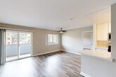 This single-floor, 2-bedroom, 2-bathroom residence offers a practical and comfortable layout throughout. The open living area is finished with wood-style plank flooring and neutral beige-toned walls, creating a clean, versatile backdrop. A ceiling fan is centrally positioned overhead, and large windows alongside a sliding glass door flood the space with natural light while providing access to an outdoor area with exterior views. The kitchen is designed in a galley configuration, featuring white shaker cabinetry, light quartz countertops, stainless steel appliances including a gas range, microwave, and refrigerator, as well as a undermount sink — a functional and modern setup well-suited for everyday use.

The primary bedroom is generously proportioned, offering ample space for furnishings, and is equipped with a dedicated closet featuring continuous rod shelving and wood-style flooring. The second bedroom similarly benefits from its own closet. Both bathrooms are finished in clean white tones; at least one includes a full tub-shower combination with a curved rod, a white vanity, and tile flooring. Throughout the unit, consistent flooring and a neutral color palette contribute to a cohesive and move-in ready aesthetic.