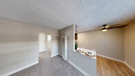 Located at 6263 Acorn Street in San Diego, CA, this single-floor, 2-bedroom unit offers a practical and well-appointed layout. The living area features soft carpet flooring and neutral taupe-toned walls, creating a warm and cohesive atmosphere throughout. A textured ceiling is consistent across the space, lending a classic residential character.

The kitchen is a standout feature, outfitted with modern gray shaker-style cabinetry, white countertops, and stainless steel appliances including a refrigerator, over-the-range microwave, and a gas range. Light wood-look flooring and a single-basin sink with a matte black faucet complete the functional and stylish cooking space. A pass-through counter connects the kitchen to the dining and living area, making the space feel open and connected.

The primary bedroom is generously proportioned and includes a mirrored sliding-door closet, providing ample storage. Both bedrooms are carpeted and feature neutral walls and natural light from windows fitted with horizontal blinds. The hallway connects the bedrooms efficiently to the rest of the unit.

A ceiling fan is present in the main living area, and a wall-mounted heating unit adds to the home's functional amenities. Overall, the unit presents a clean, move-in-ready environment with updated finishes throughout.