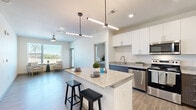 Located at 733 N Drennan St in Houston's 77003 zip code, this well-designed two-bedroom, two-bathroom residence offers a thoughtfully laid-out single-floor plan. The open-concept kitchen serves as the heart of the home, showcasing granite countertops, a large center island with bar seating, sleek white upper cabinetry, dark lower cabinetry, and a full suite of stainless steel appliances including a refrigerator, range, microwave, and dishwasher. Modern linear pendant lighting and recessed fixtures illuminate the space. The kitchen flows seamlessly into the living area, which features light wood-style flooring, a ceiling fan, and a large window that brings in generous natural light and outdoor views. Both bedrooms are carpeted and offer a calm, neutral palette, with one bedroom featuring a dedicated window with natural light. The primary bathroom includes a granite-topped vanity with dark cabinetry, a tub and shower combo, and open wire shelving for storage. The secondary bathroom mirrors the modern aesthetic with a tiled walk-in shower, granite vanity, and wood-style flooring. Two closets and an in-unit washer are also included, adding everyday convenience to this efficient and stylish Houston residence.