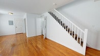 Located at 76 Litton Ct within the Groton Townhouses community in Groton, Connecticut, this two-story townhouse offers a straightforward and functional layout with consistently warm, polished hardwood flooring throughout the main living areas and upper level. The first floor presents an open, airy feel, with crisp white walls that reflect natural light filtering in through multiple windows. A white-railed staircase anchors the main living space and leads to the second floor, while a utility panel is conveniently positioned near the entry. Radiator heating units are present in several rooms, providing reliable warmth throughout the home.

The kitchen features rich, dark mahogany-toned cabinetry paired with granite countertops and a decorative tile backsplash in neutral tones of gray and beige. A corner stainless steel sink and modern hardware complete the space, giving it a polished, updated appearance.

The bathroom is finished in clean white tile, including a full soaking tub with shower, a white basin sink set into a dark wood vanity with a framed mirror, and a window that introduces natural light. Bedrooms on the upper level continue the hardwood flooring theme and feature multiple windows, radiator heating, and neutral walls, creating bright and versatile spaces throughout.