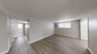 Located in Lexington, KY, this single-floor home offers four bedrooms, one bathroom, a living room, dining room, kitchen, and entrance — all connected by a series of hallways that create a practical and efficient layout. Throughout the main living areas, durable wood-look flooring and neutral gray walls establish a clean, modern aesthetic complemented by textured ceilings and crisp white trim.

The spacious living room features a wall-mounted air conditioning unit and a window with blinds that brings in natural light, while an adjacent open area provides flexible space for dining or additional seating. The galley-style kitchen is well-appointed with white cabinetry featuring black hardware, granite-look countertops, a stainless steel sink, subway tile backsplash, and black stainless appliances including a gas range and refrigerator — with a window at the far end adding brightness.

The four bedrooms are finished with plush carpet flooring and neutral gray walls, each featuring textured ceilings and windows with blinds for natural light. The primary bedroom offers a generous footprint for comfortable furnishing. The bathroom includes a vanity with light countertops, gray cabinetry with gold hardware, a tub/shower combination, and direct hallway access, maintaining the home's cohesive, updated style throughout.