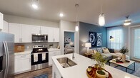 This well-appointed two-bedroom, two-bathroom residence in College Station, Texas, offers a thoughtfully designed single-floor layout that balances modern aesthetics with functional living. The open-concept kitchen and living area serves as the heart of the home, where crisp white shaker cabinetry, quartz countertops, and a large center island with an undermount sink create an inviting culinary space. Stainless steel appliances, including a side-by-side refrigerator, electric range, and built-in microwave, complete the kitchen. Pendant lighting above the island adds a stylish finishing touch. Wood-style flooring runs throughout the main living areas, while the living room features a bold teal accent wall and a glass door that welcomes natural light.

Both bedrooms offer plush carpeting, natural light from well-positioned windows, and generous closet space, including a walk-in closet in the primary bedroom. Each bathroom is finished with white dual-sink vanities, quartz countertops, wood-style flooring, and tiled tub-shower combinations, delivering a clean, contemporary feel throughout. The cohesive design palette and quality finishes make this a polished and comfortable residence.
