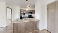 Located at 5317 W Pine Ridge Dr in Sioux Falls, South Dakota, this 2-bedroom, 2-bathroom single-floor residence offers a well-planned layout designed for comfortable everyday living. The open-concept kitchen flows seamlessly into the living area, creating a bright and connected space filled with natural light from a sliding glass door that leads to a private balcony. The kitchen features dark cabinetry with brushed hardware, a peninsula with a double stainless steel sink, pendant lighting, and black appliances including a refrigerator, range, microwave, and dishwasher. Durable wood-look flooring runs throughout the kitchen and living areas, while plush carpeting adds warmth to the bedrooms. Both bedrooms are well-proportioned, each offering natural light through large windows with views of the surrounding neighborhood. The primary bedroom is generously sized with dedicated closet space. The two bathrooms are appointed with dark vanity cabinetry, tile flooring, and full tub-shower combinations. A dedicated in-unit laundry room includes a full-size washer and dryer, adding everyday convenience. Three closets throughout the unit provide ample storage. The space maintains a clean, neutral palette throughout, contributing to a bright and welcoming atmosphere.