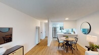 This single-floor residence offers a thoughtfully designed layout that balances comfort and functionality throughout. A welcoming entry hallway, finished with light wood-tone flooring and clean white walls, leads into the main living areas. The living room is bright and inviting, featuring a large window dressed with patterned grommet curtains and wood blinds that frame views of the surrounding greenery, allowing natural light to fill the space. The open-concept dining area sits adjacent to the kitchen, separated by a convenient breakfast bar with white countertops. The kitchen is well-equipped with white cabinetry accented by matte black hardware, a stainless steel sink and appliances including a refrigerator and dishwasher, and a window that brings in additional natural light. The bedroom is a comfortable retreat with plush carpet flooring, a textured ceiling, and a built-in sliding-door closet. A standout feature is the sliding glass door that opens directly to a private outdoor patio. The bathroom is clean and modern, offering a white vanity with an undermount sink, a medicine cabinet with mirror, and a shower-tub combo. Light wood-tone flooring flows consistently through the main living areas, contributing to a cohesive and contemporary aesthetic throughout.